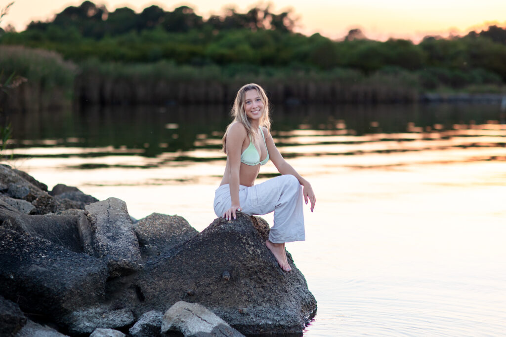 senior portrait young girl sitting on rock over looking the bay in virginia beach at sunset. brooke tucker photography