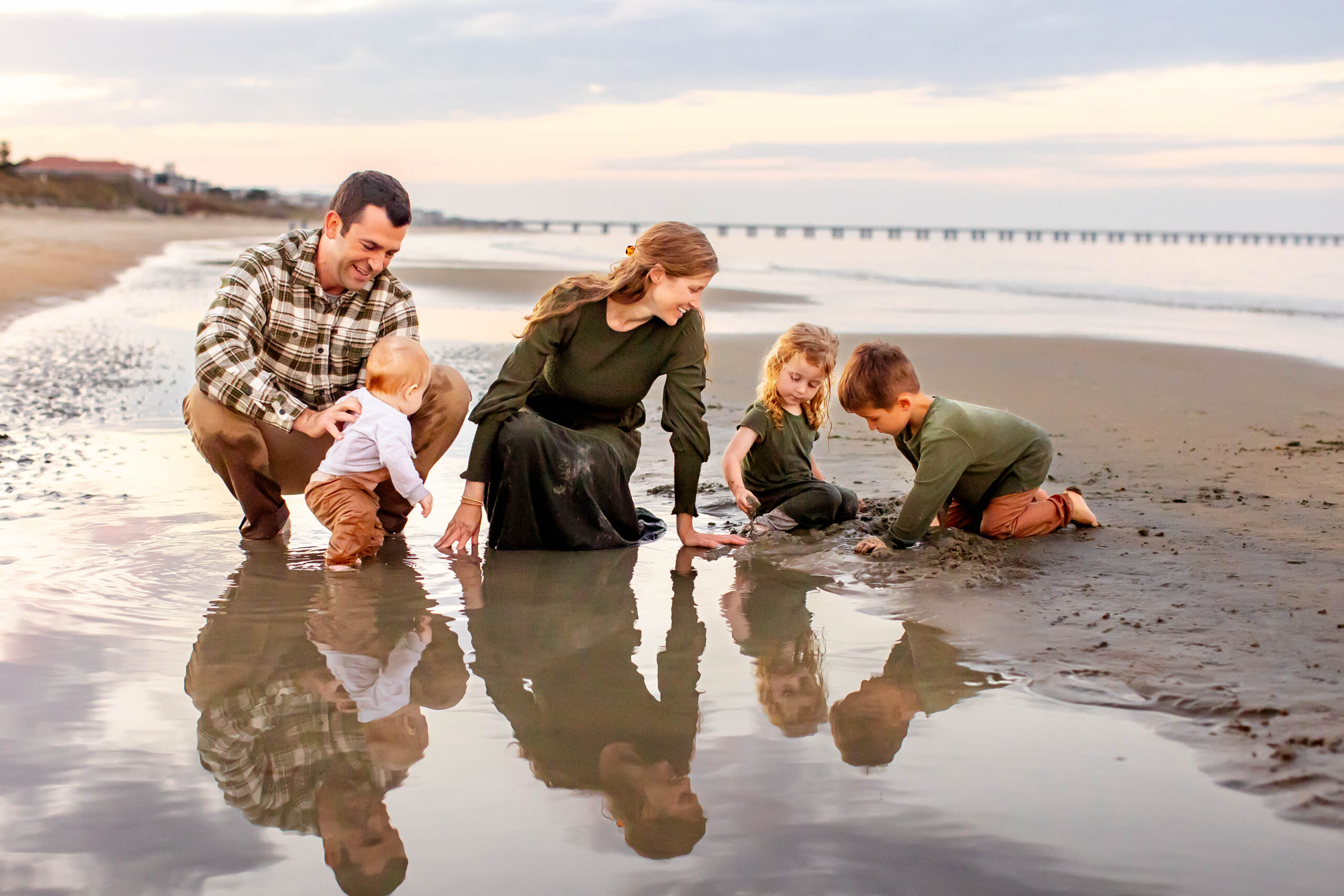 beautiful young family of five plays in a tidal pool during the golden hour during a playful, candid family photography session in virginia beach