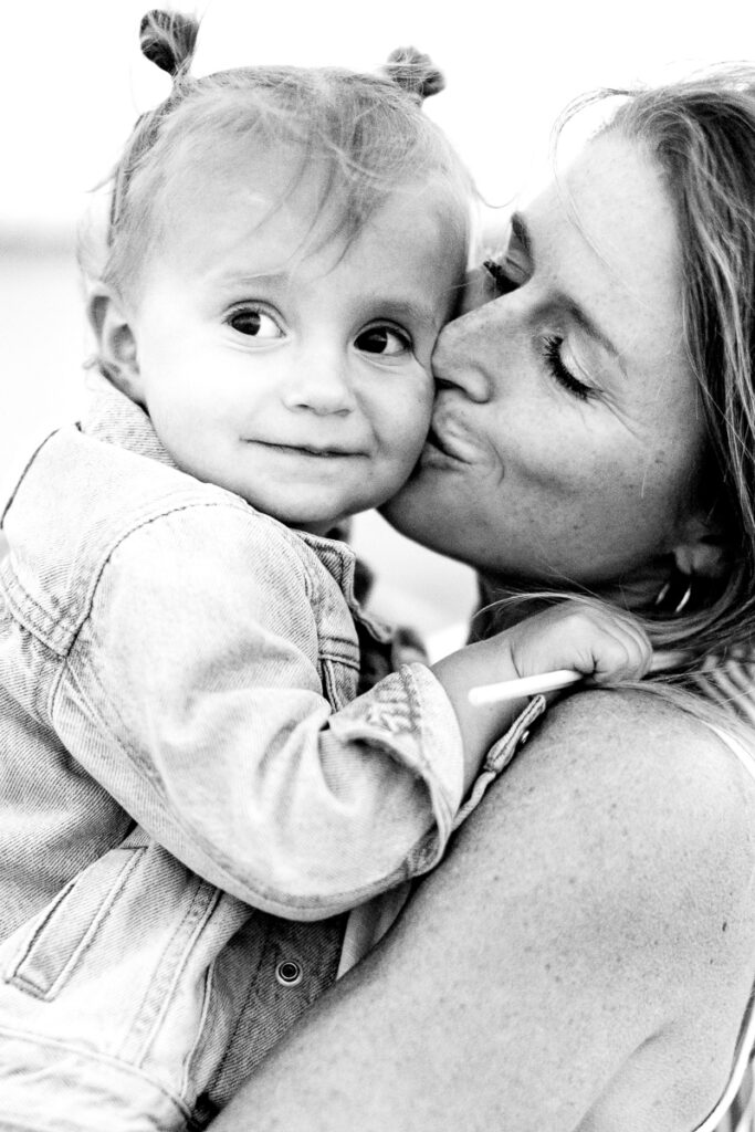 A black and white image of a mother holding her toddler close during a quiet beach moment